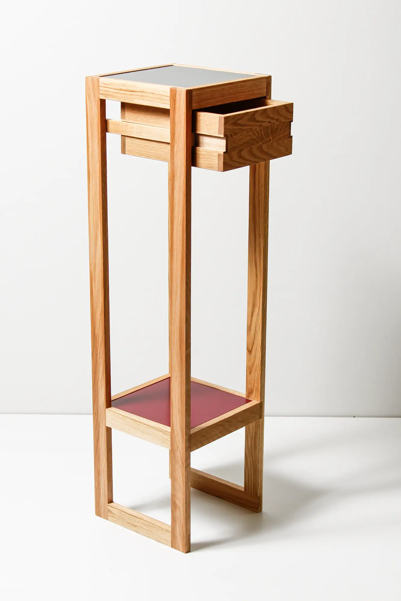 Hohes, minimalistisches Holzsäule mit einem Schubladenfach oben und einer Ablagefläche unten.