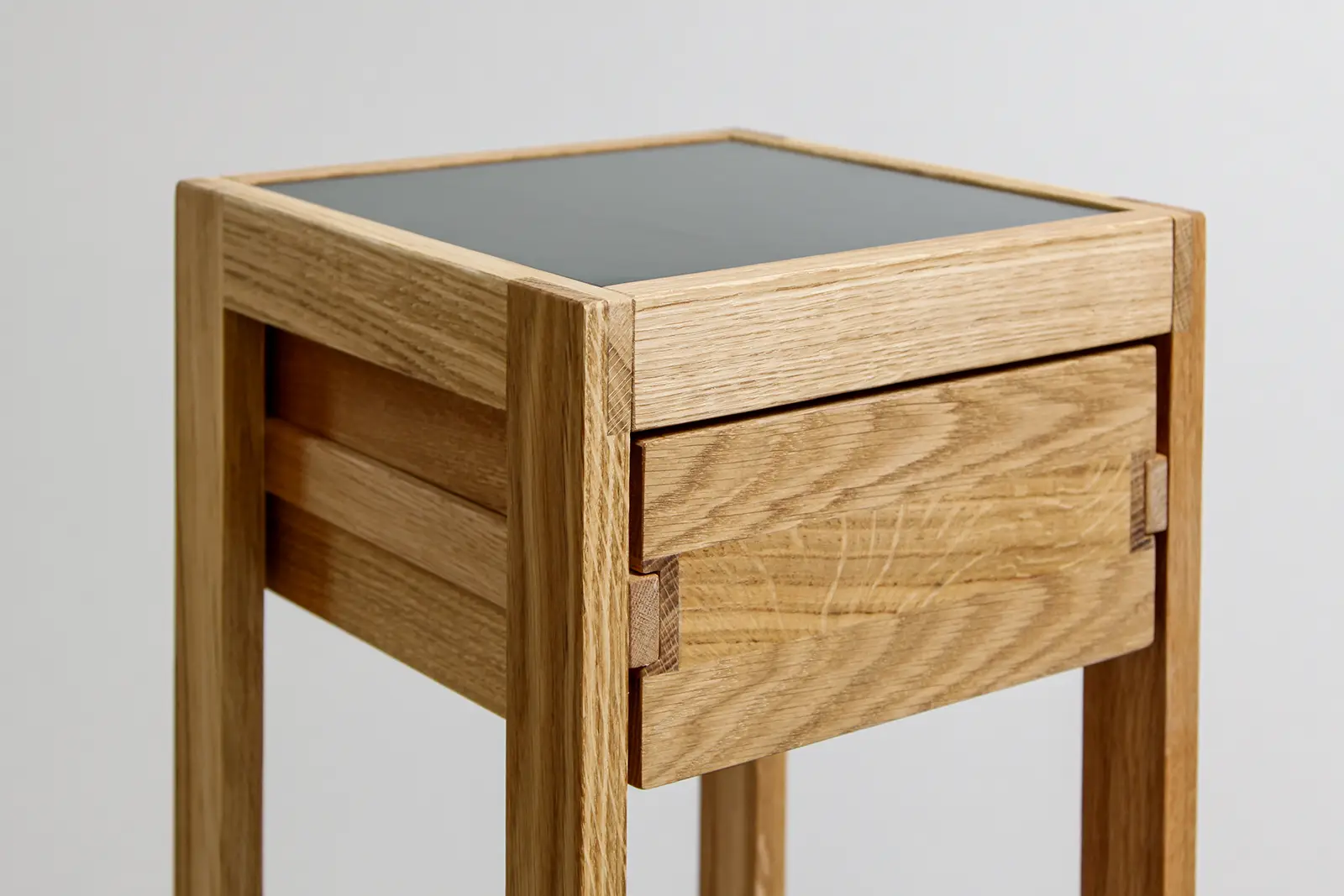 Moderner Beistelltisch aus hellem Holz mit quadratischer Tischplatte und Schublade.