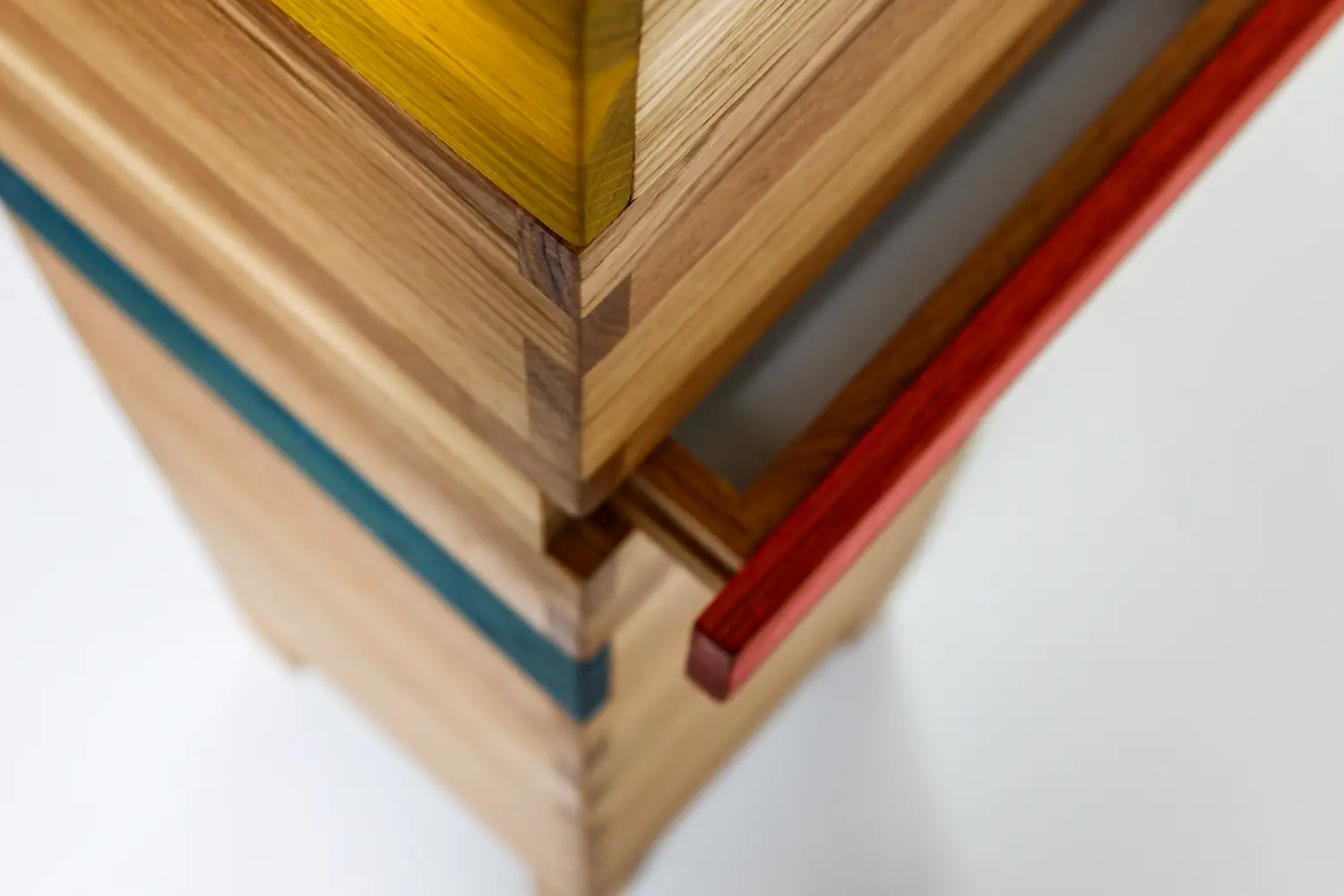 Detailaufnahme einer Holzsäule mit eingefärbten farbigen Akzenten in Gelb, Blau und Rot.